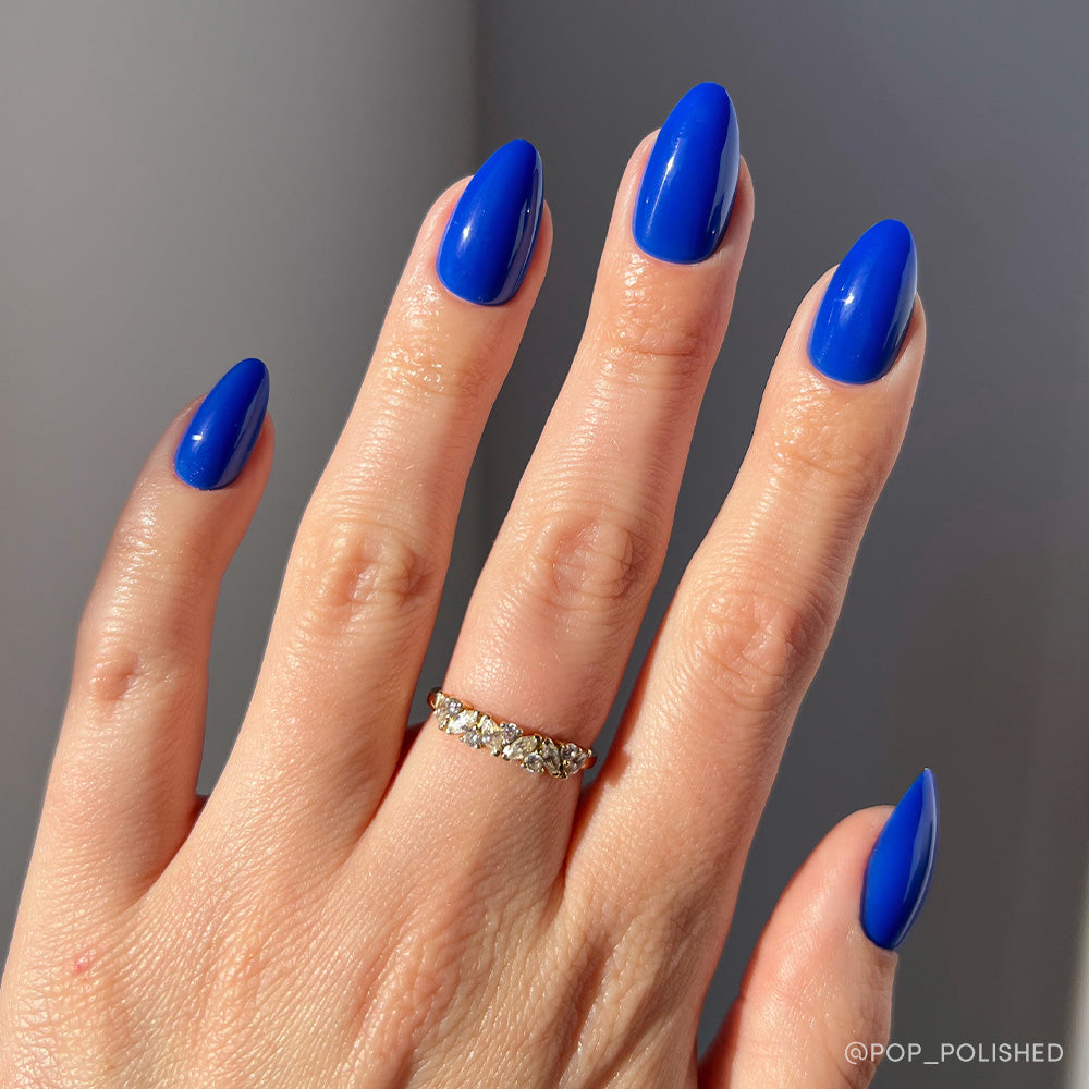 Hand with blue nail polish on a gray background