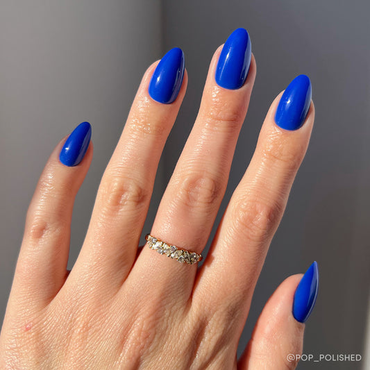 Hand with blue nail polish on a gray background